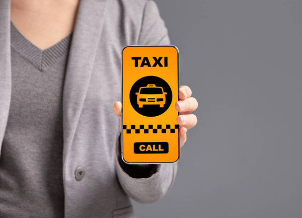 Жінка показує смартфон з інтерфейсом додатка таксі
 - Фото, зображення