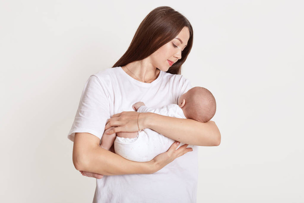 Young happy attractive mother hold little daughter, brown haired lady looking with gentle and love at her baby, posing isolated over white background. - Foto, Imagem