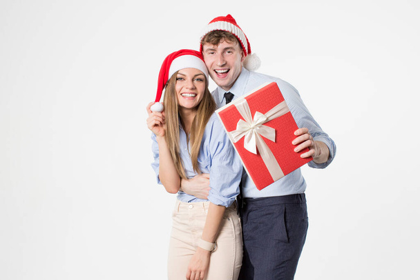 Christmas holiday happy couple hold present gift box wear red new year santa hat, man and woman love smile looking at camera embracing, isolated over white background. - Φωτογραφία, εικόνα