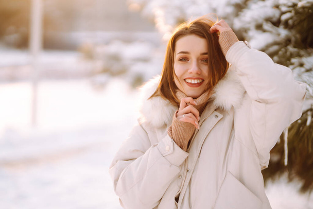 Jonge mooie vrouw poserend in een besneeuwd park. Koud weer. Winter mode, vakantie, rust, reizen concept. - Foto, afbeelding