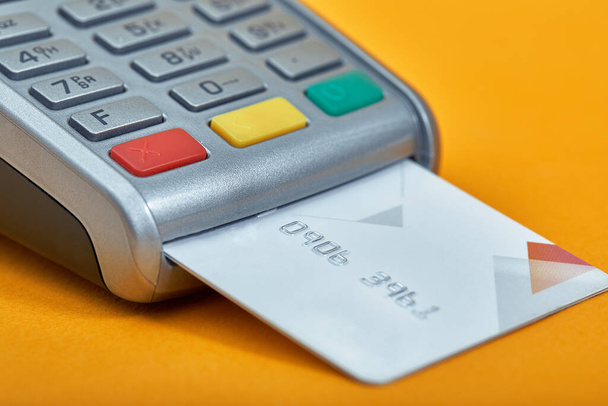 Payment by credit card. Terminal on yellow background copy space - Foto, imagen