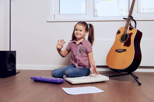 a little girl learns to play the guitar from notes. Music school for children.Musical notation. - Foto, Imagem