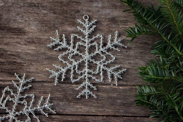 Schneeflocken auf Holztisch draußen mit Eibenzweig perlen - Foto, Bild