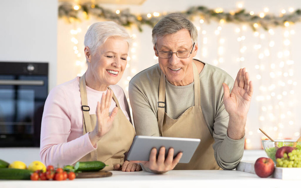 Seniorenpaar winkt dem Tablet mit Videotelefonie ins Haus - Foto, Bild