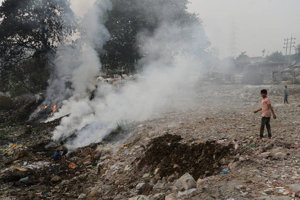 Children playing as garbage burns create toxic smoke on the bank of Buriganga River in Dhaka, Bangladesh, on December 6, 2020. Dhaka continues to be ranked as one of the world's most polluted cities. - Photo, Image