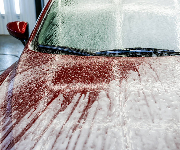 Washing red car with active foam at car wash service. - Fotografie, Obrázek