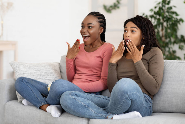 Korkmuş siyah kız arkadaşlar evde birlikte korku izliyorlar. - Fotoğraf, Görsel