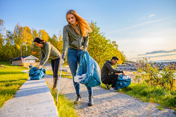 Ehrenamtliches Team sammelt Müll in Tüte am Strand - Foto, Bild