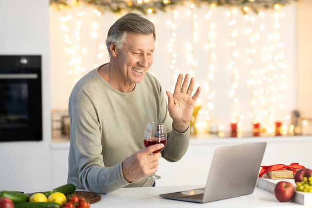 Старший мужчина, имеющий видео-звонок празднование Рождества на кухне в помещении - Фото, изображение