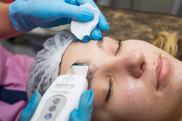Detailní záběr krásné ženy přijímající ultrazvuk kavitace obličeje peeling. Ultrazvukové čištění kůže. Kosmetická léčba. Krása, lázně, kosmetika a péče o pleť. Kosmetická klinika. - Fotografie, Obrázek