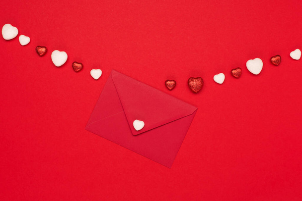 バレンタイン、誕生日、女性、母の日のためのお祭りの休日の挨拶カード。赤い白いハートと赤い背景の空の封筒。バレンタインデーのコンセプト。フラットレイアウト、トップビュー、コピースペース. - 写真・画像