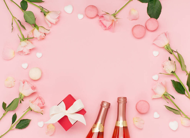 Festive holiday greeting card for Valentines, Birthday, Woman or Mothers Day. Flowers, bottle of wine, sweets and gift on pink background. Valentines day concept. Flat lay, top view, copy space. - Foto, Bild