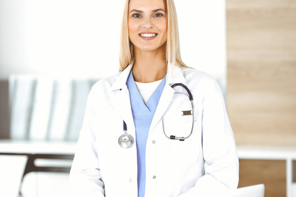 Woman-doctor at work in clinic happy of her profession. Blond female physician controls medication history record and medical exam results. Medicine concept - Foto, Imagem