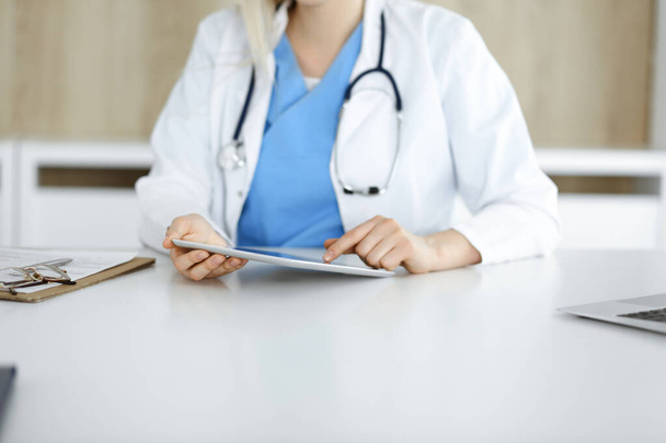 Unknown woman-doctor standing in clinic and using tablet pc, close-up. Data and best service in medicine and healthcare - Foto, Imagen