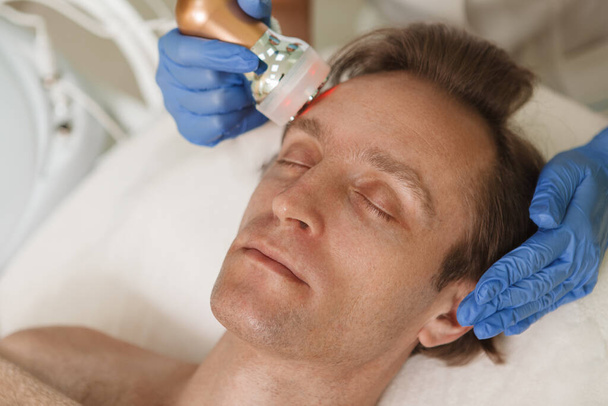 Dojrzałe mężczyzna relaks podczas rf-lifting twarzy procedury w klinice dermatologii - Zdjęcie, obraz