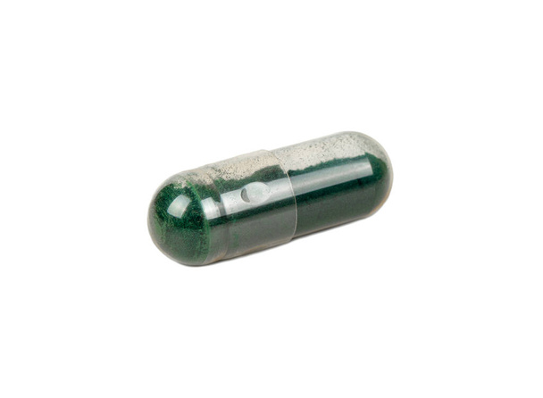 Transparante capsule met geneeskrachtig groen gras geïsoleerd op een witte achtergrond - Foto, afbeelding