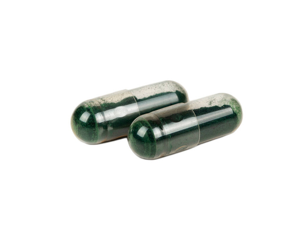 Twee groene capsules geïsoleerd op een witte achtergrond - Foto, afbeelding
