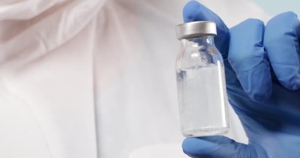 Ученый в синих нитрильных перчатках держит вакцину от гриппа, кори, коронавируса. Разработка и создание коронавирусной вакцины COVID-19. - Кадры, видео