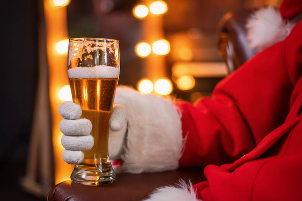 Close-up of santa claus hand with a pint of light beer. Merry Christmas - Foto, Imagem
