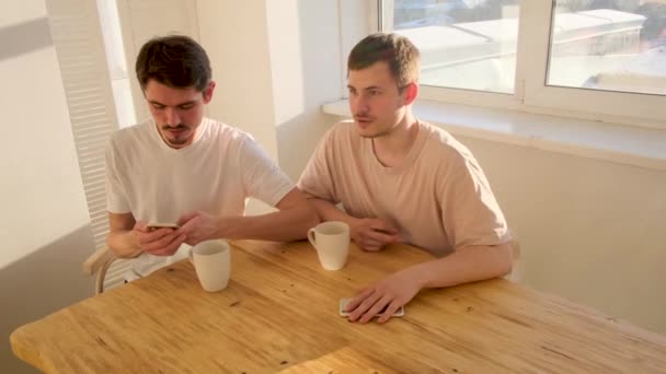Un par de hombres están sentados en la mesa con teléfonos inteligentes - Imágenes, Vídeo