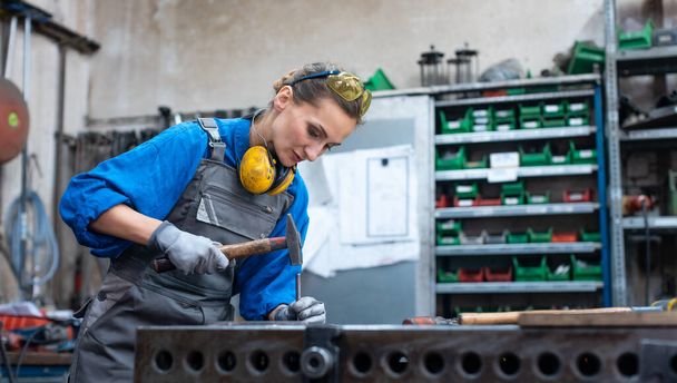 Metal işçisi kadın çelik parçasını işaretliyor. - Fotoğraf, Görsel