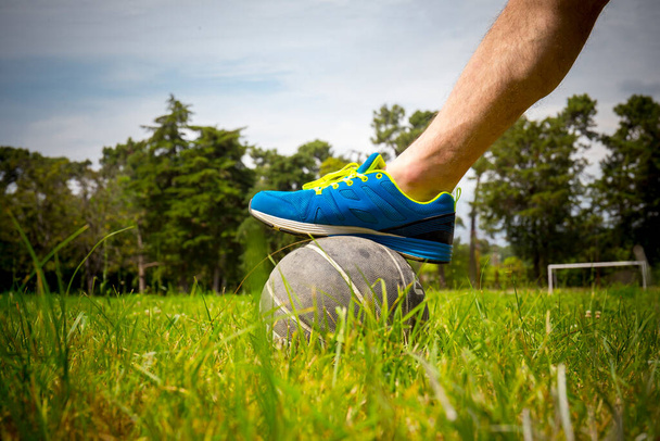 Fußballer kickt auf naturbelassenem grünen Feld - Foto, Bild
