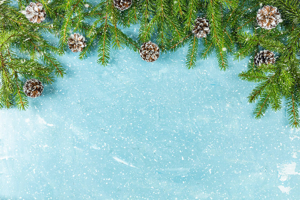 Karácsonyi vagy újévi háttér zöld fenyő ágak és kúpok kék háttérrel. Téli koncepció, felülnézet, másolás - Fotó, kép