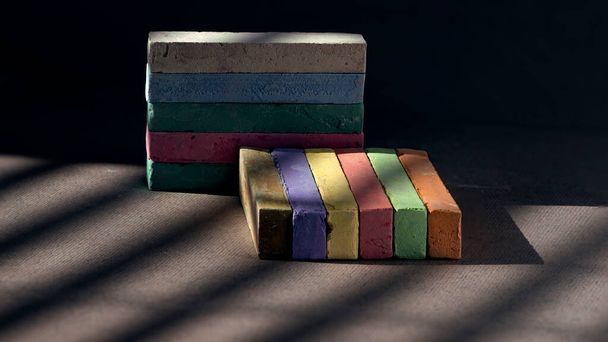 Colorful chalk spread on dark background.For student,teacher,children or who want to draw something.School family.Shadows form a pattern with colored chalk. - Valokuva, kuva