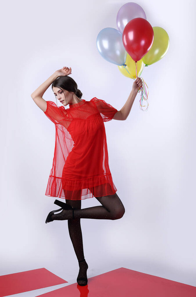 Tytöt punaisessa mekossa ja mustat sukkahousut ilmapalloilla kevyellä taustalla - Valokuva, kuva