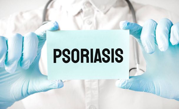 Doctor holding card in hands and pointing the word PSORIASIS - Foto, afbeelding