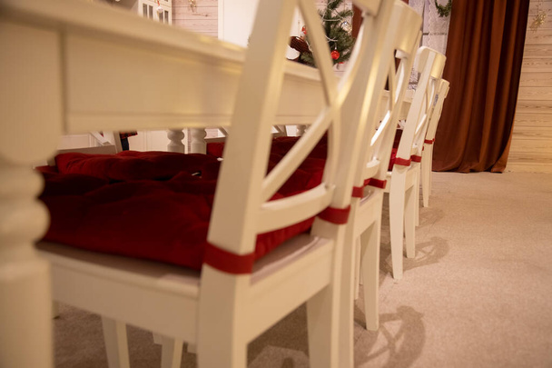close-up de mesa de jantar branca com travesseiro vermelho no fundo do interior festivo celebração do ano novo - Foto, Imagem