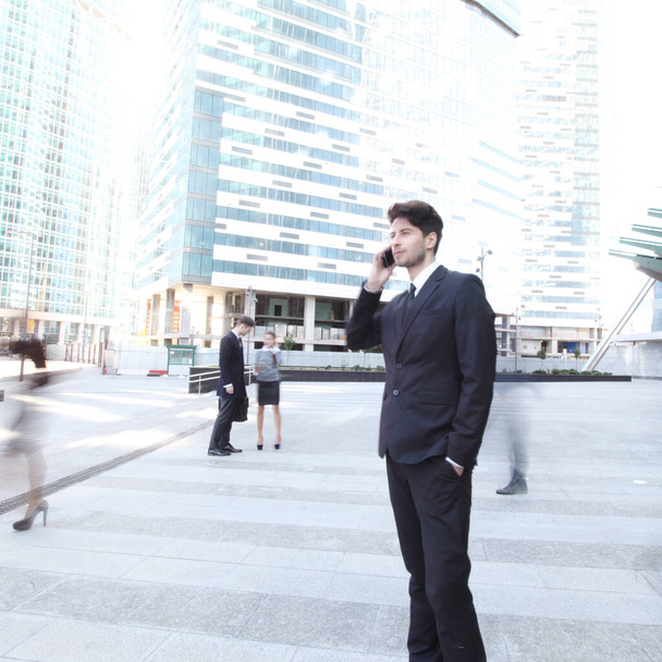 Handsome businessman talking on the cellphone outside office building - Foto, imagen