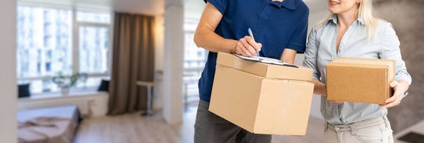 woman receiving boxes from postman at the door in home delivery concept. Woman received the parcel from the postman at home. Postman giving cardboard box to young woman. - Foto, imagen