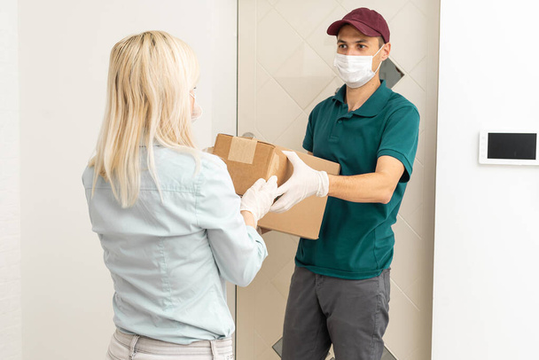 Woman and courier during order transfer. Woman accepting delivery from deliveryman. Cropped image of delivery service worker giving parcel to client. - Foto, Imagen