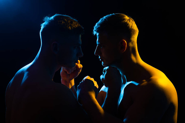 Aggressive man. Confrontation. Two brutal man looking into each others isolated on black. - Foto, afbeelding