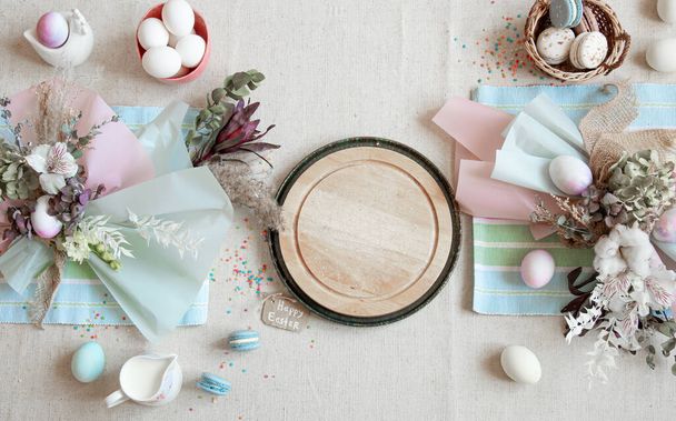 Easter composition with flowers, eggs and wooden space for text in pastel colors flat lay. - 写真・画像
