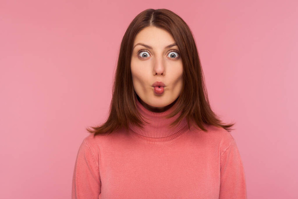 Closeup portrait attractive brunette woman in pink sweater fooling around making fish lips, having fun, humor. Indoor studio shot isolated on pink background - Photo, image