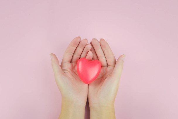 Woman Holding Heart Shape Over Pink Background, health care, donate and family insurance concept, world health day, Valentine day concept - Photo, Image