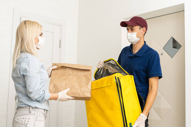 Deliveryman of goods and parcels to customers by protecting them with medical masks and gloves. Online shopping order under quarantine coronavirus covid-19 - Photo, Image