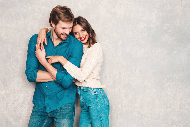 Portrait of smiling beautiful woman and her handsome boyfriend. Happy cheerful family posing in studio near gray wall.Valentine's Day. Models hugging. Concept of love - Photo, Image
