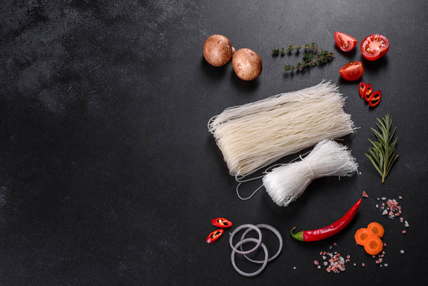 Sabrosos fideos de arroz con tomate, pimiento rojo, champiñones y mariscos sobre un fondo de hormigón oscuro - Foto, Imagen