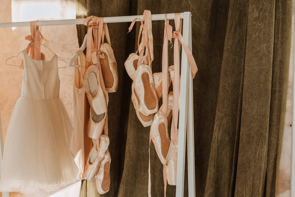 Spitzenschuhe, Ballettkleid, das am Rang hängt. Ballettbarre in der Nähe des Spiegels - Foto, Bild