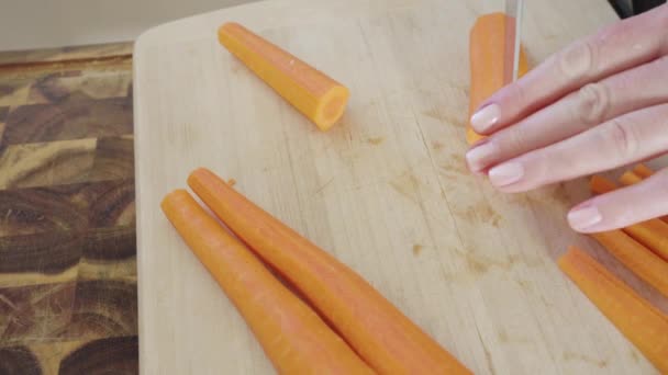 Резка большой оранжевой морковки на деревянной доске. - Кадры, видео