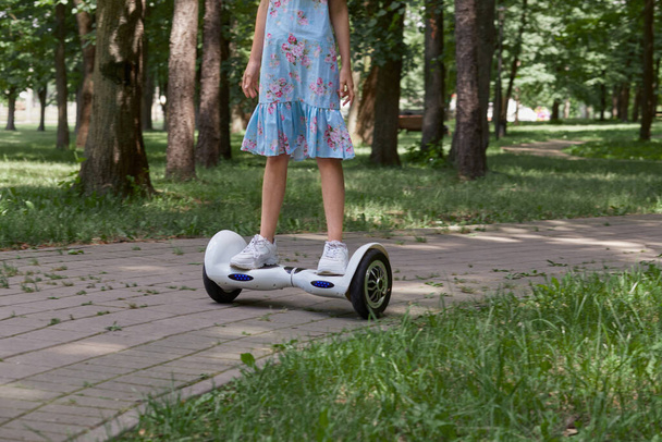 A teenage girl in white sneakers on a gyro scooter ride through the Park. - Foto, Imagem