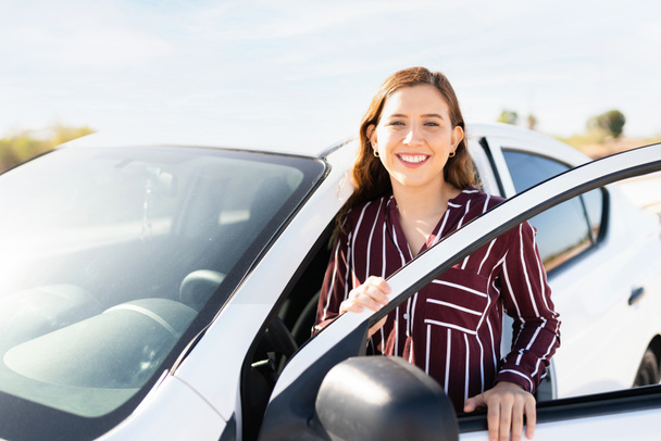 20 'li yaşlarda güzel sarışın bir kadının portresi gülümsüyor ve arabasının sürücü koltuğuna oturuyor.  - Fotoğraf, Görsel