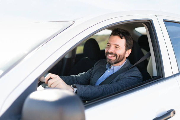 Heureux homme hispanique conduisant sur l'autoroute avec les deux mains sur le volant et portant une ceinture de sécurité  - Photo, image