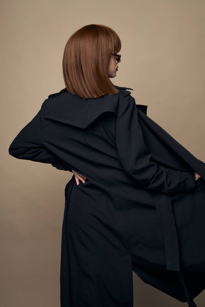 Mulher sexy casaco escuro bom humor rindo em um fundo bege  - Foto, Imagem