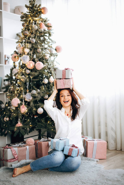 Hermosa chica feliz año nuevo regalos cerca del árbol de Navidad. Emociones alegres - Foto, imagen