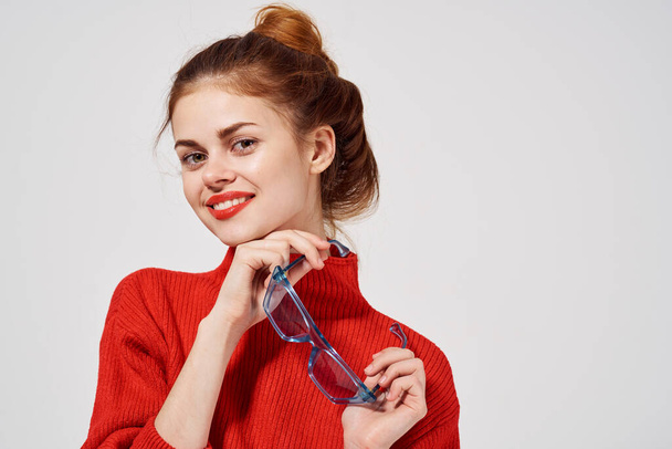 手の中にメガネを持つ陽気な女性感情モデル赤いセーター - 写真・画像