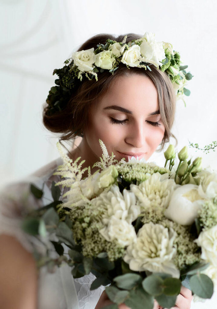 Young beautiful bride with a wedding bouquet and an elegant wreath in her hair. Soft focus and blurry bokeh - Valokuva, kuva